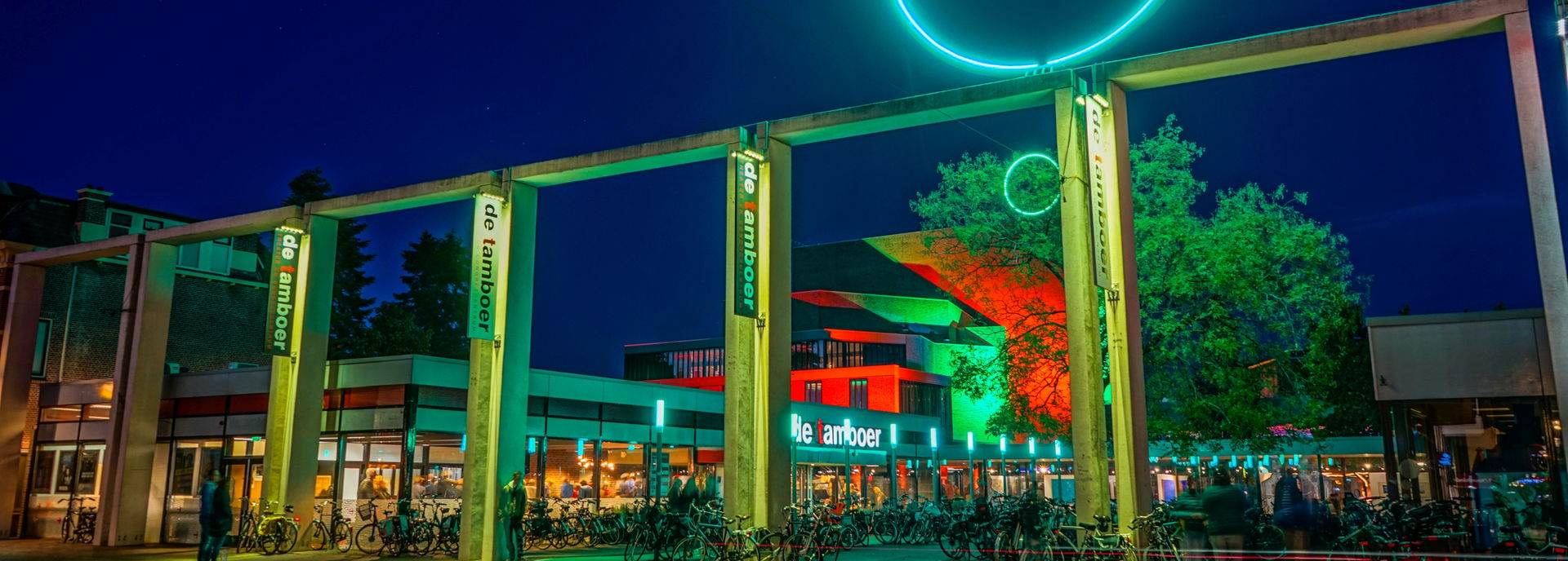 Het gebouw van Theater De Tamboer, gefotografeerd van buiten in de avond. 