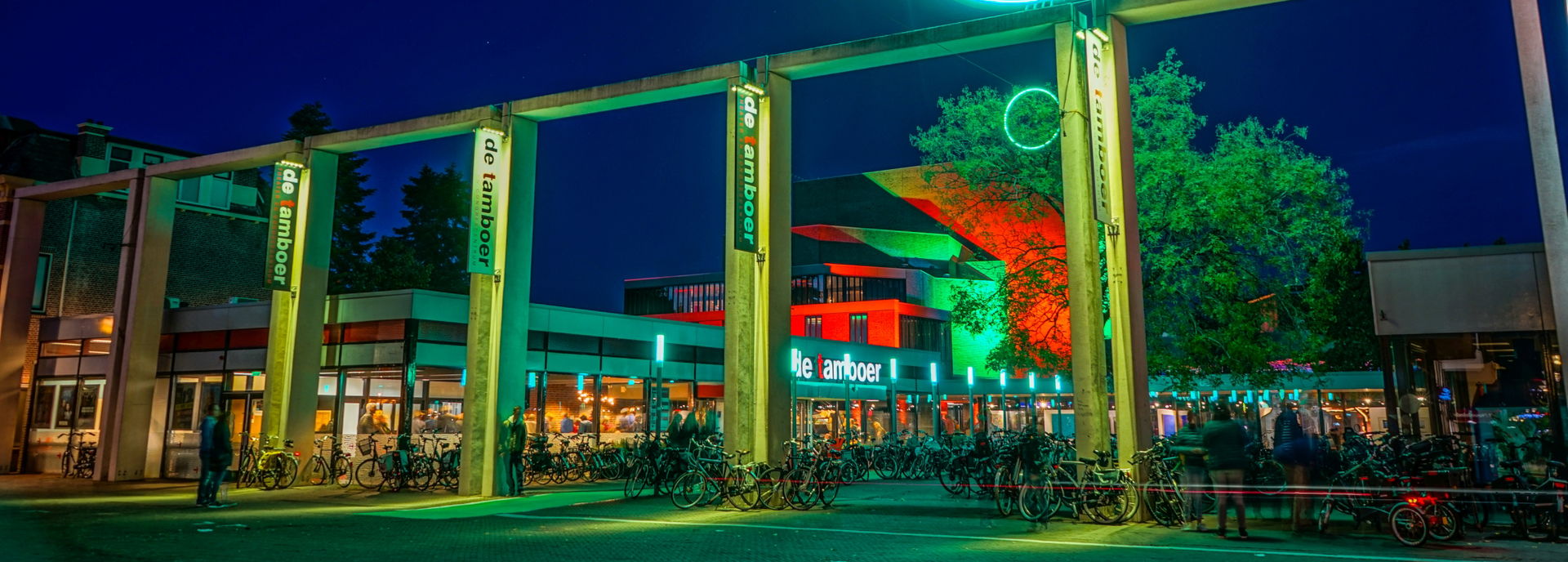 Het gebouw van Theater De Tamboer, gefotografeerd van buiten in de avond. 